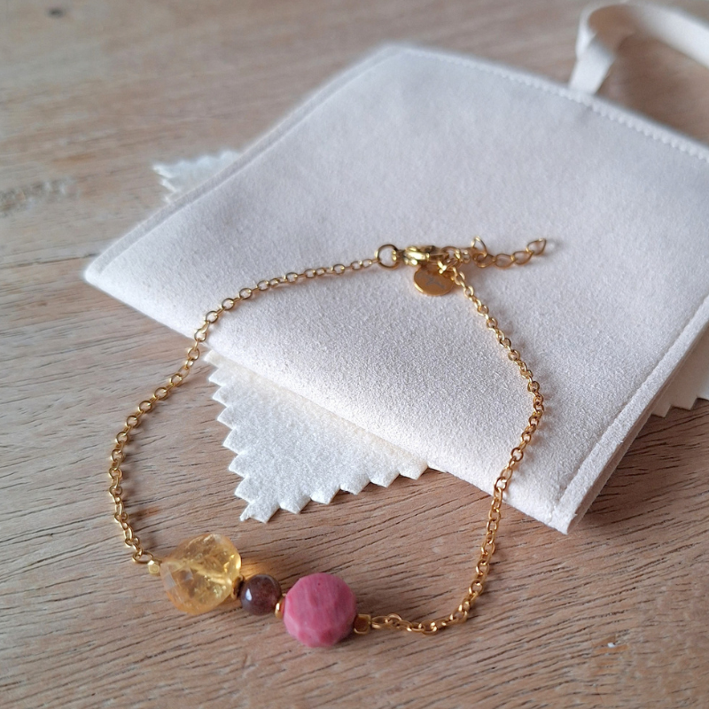 Close-up van citrien armband met donkerbruine agaat, roze rhodoniet en goudkleurige hematiet op fluweel