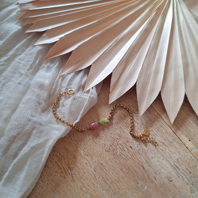 Aardbeienkwarts en peridoot armband in zacht licht op hout