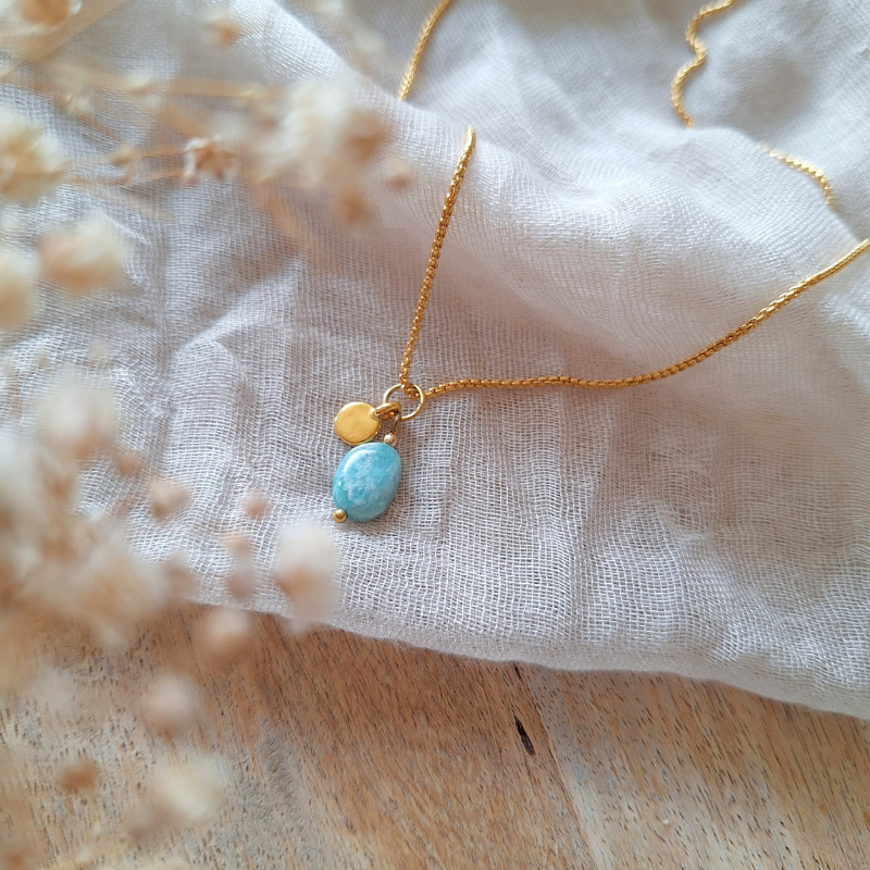 Amazoniet ketting met gouden bedeltje op lichte stof