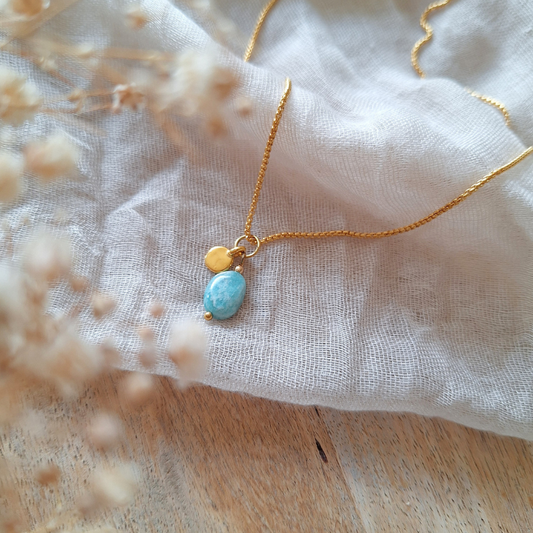 Amazoniet ketting met gouden bedeltje op lichte stof