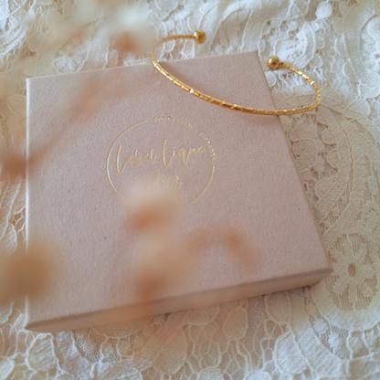Gouden bangle met fijn werkje op een sieradendoosje