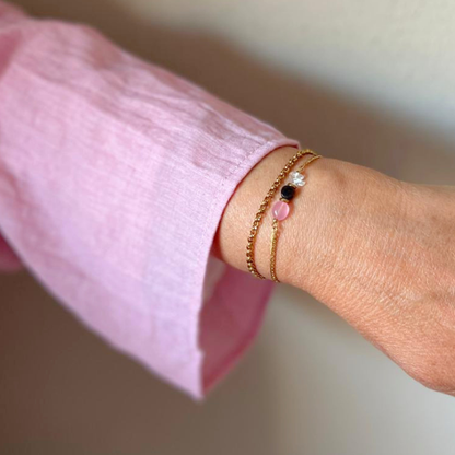 Rozenkwarts opaline armband met goud om pols