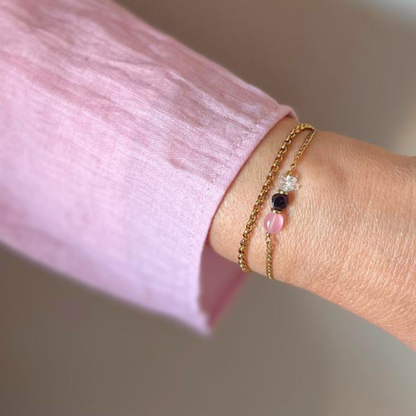Rozenkwarts opaline armband goldfilled gedragen om vrouwelijke pols in zacht licht
