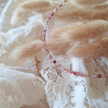 Andesine armband met rode edelstenen en goudkleurige hematiet, gefotografeerd op droogbloemen en kant.