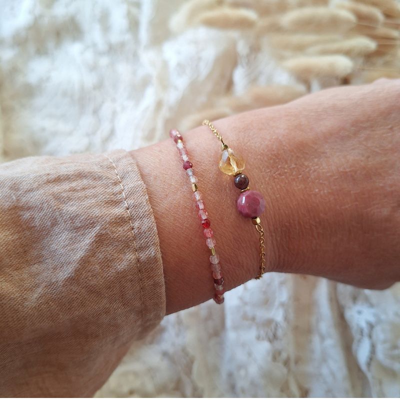 Andesine armband met glinsterende rode edelstenen en goudkleurige hematiet, gedragen om de pols.