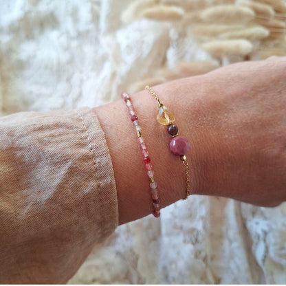 Andesine armband met glinsterende rode edelstenen en goudkleurige hematiet, gedragen om de pols.