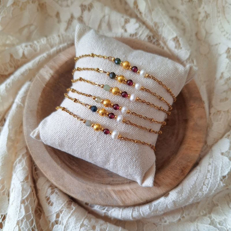 Meerdere handgemaakte armbanden Geloof in Jezelf op een sieradenkussentje.