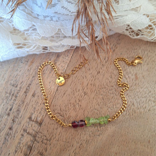 Granaat armband met facetgeslepen muntkralen, groene peridoot chips en goudkleurige hematiet, op hout met kant.